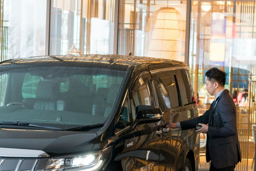 A chauffeur in a suit standing beside a black car